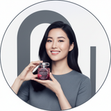 Circular portrait of Sofia Chen holding the Jimmy Choo Blossom Eau de Parfum. She smiles confidently against a clean, bright 